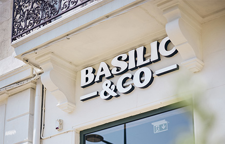 Logo Basilic & Co en blanc en guise d'enseigne sur la façade de l'une des implantations de la marque